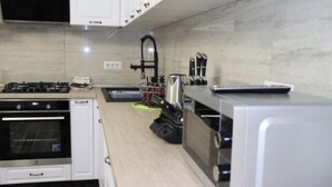 Una cocina con estufa a gas, horno, microondas y lavamanos.