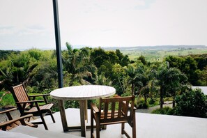 Une table et des chaises en bois sur un balcon offrant une vue sur un paysage luxuriant.