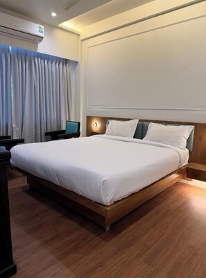 Ein Hotelzimmer mit einem großen Bett, einem Schreibtisch und einer Klimaanlage.