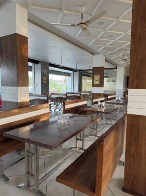 Eine moderne Cafeteria mit langen Gemeinschaftstischen, Bänken und Deckenventilatoren.