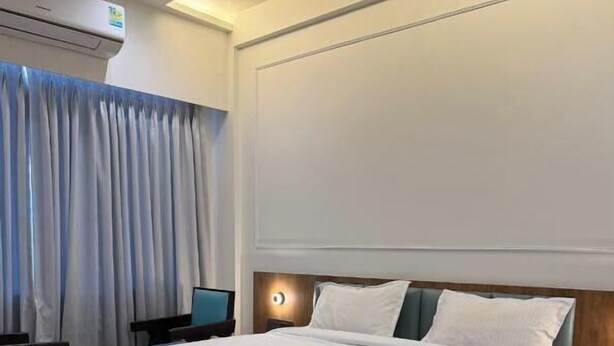 Une chambre d’hôtel avec un grand lit, un bureau, une chaise, une table de chevet et un appareil de climatisation.