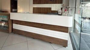 Un comptoir d’accueil avec un ventilateur de plafond, des armoiries sur le mur et une porte vitrée donnant sur l’extérieur.