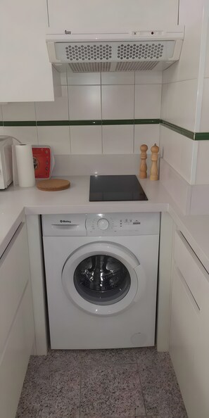 A compact kitchen with a washing machine, a toaster, a cutting board, and two salt and pepper shakers. - Vacation Apartment 'Charming Refuge in San Telmo' with Wi-Fi (Puerto de la Cruz)