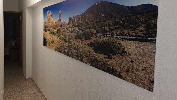 Un pasillo con un mural grande que muestra un paisaje desértico con montañas y vegetación escasa.