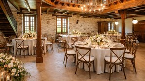 A rustic hall with wooden beams, stone walls, and a mezzanine with a balcony. Tables are set for dining with floral centerpieces. - Chateau for rent (Aix)
