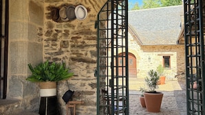 A stone building with a wooden door, potted plants, and a rustic bench. - Chateau for rent (Aix)