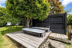 A wooden deck with two hot tubs, a tree, and a black garage door.