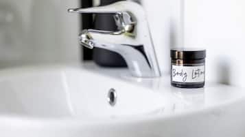 Un lavamanos con grifo cromado y un tarro de loción corporal etiquetado 'Body Lotion' sobre el mostrador.