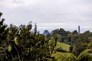 Eine Landschaft mit einem markanten Berg, einem hohen Turm und üppiger Vegetation.