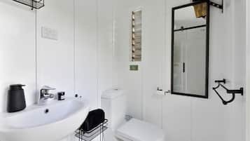 A bathroom with a white sink, toilet, and mirror.