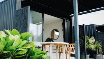 A modern outdoor seating area with a wooden table and chairs, surrounded by potted plants.