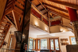A spacious interior with a high ceiling, wooden beams, and large windows.