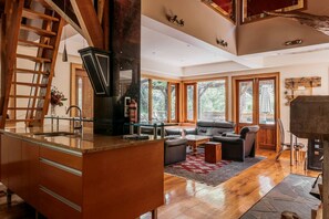 A spacious living area with a fireplace, a kitchen with a large island, and a view of the outdoors.