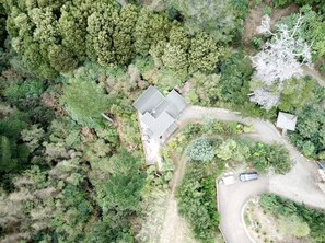 Vista aérea de una casa rodeada de bosque denso, con un camino de entrada.