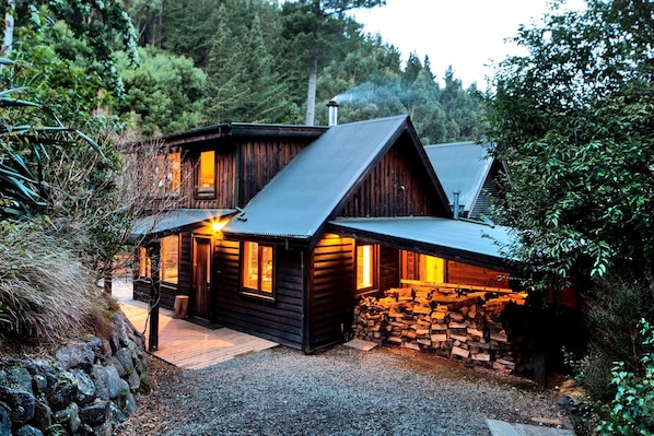 A rustic cabin with a sloped roof, wooden walls, and a stone foundation.