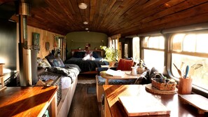 A cozy interior with a bed, seating area, and a wood-burning stove.
