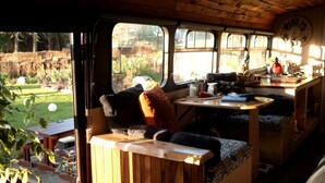 A cozy interior with a wooden bench, a table with various items, and a view of a garden through a window.
