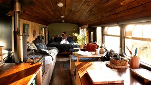 A cozy interior with a bed, seating area, and a wood-burning stove.