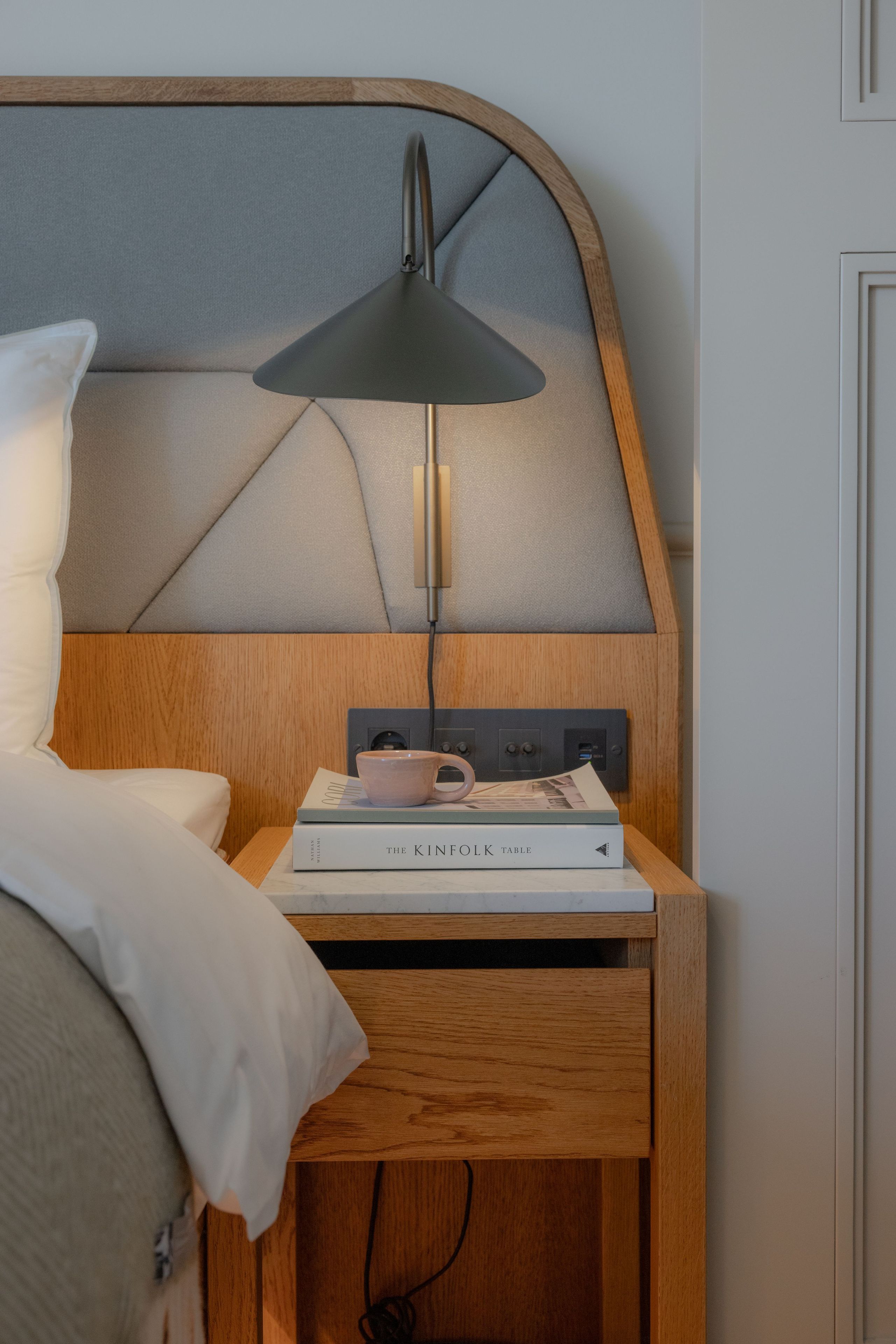 A neatly made bed with a white pillow and a wooden headboard.