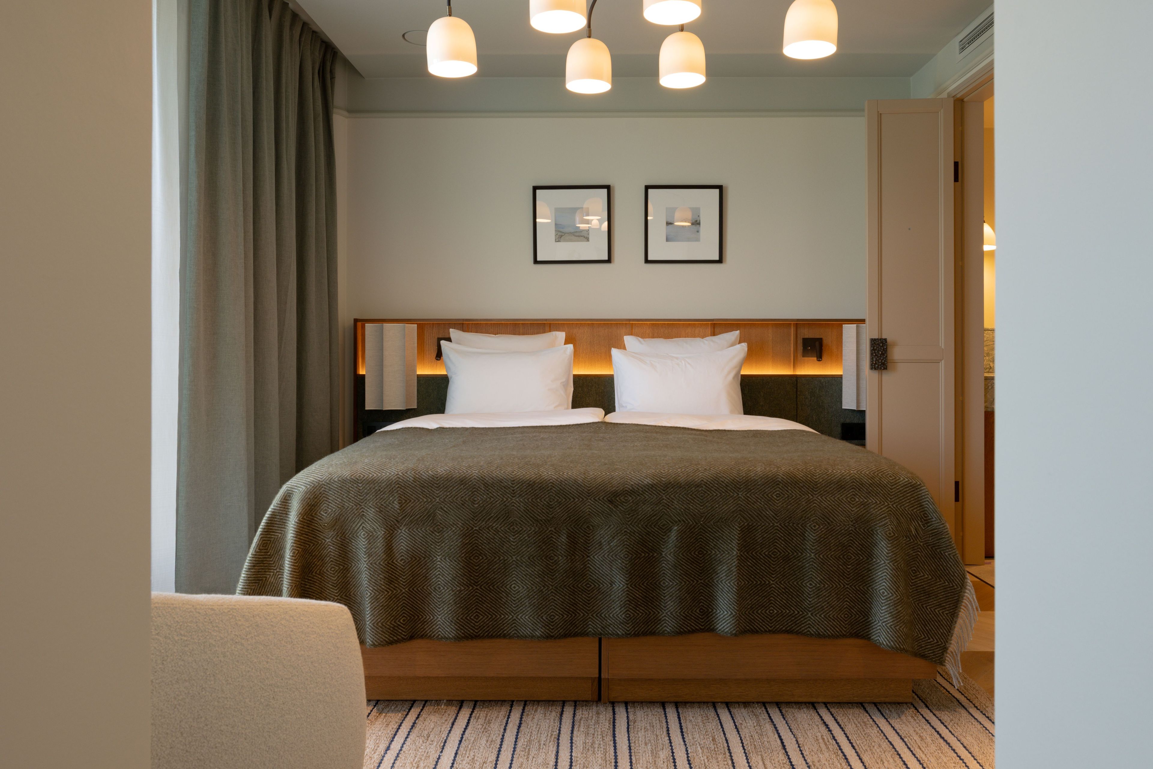 A hotel room with a large bed, a wooden headboard, and a view of the hallway.
