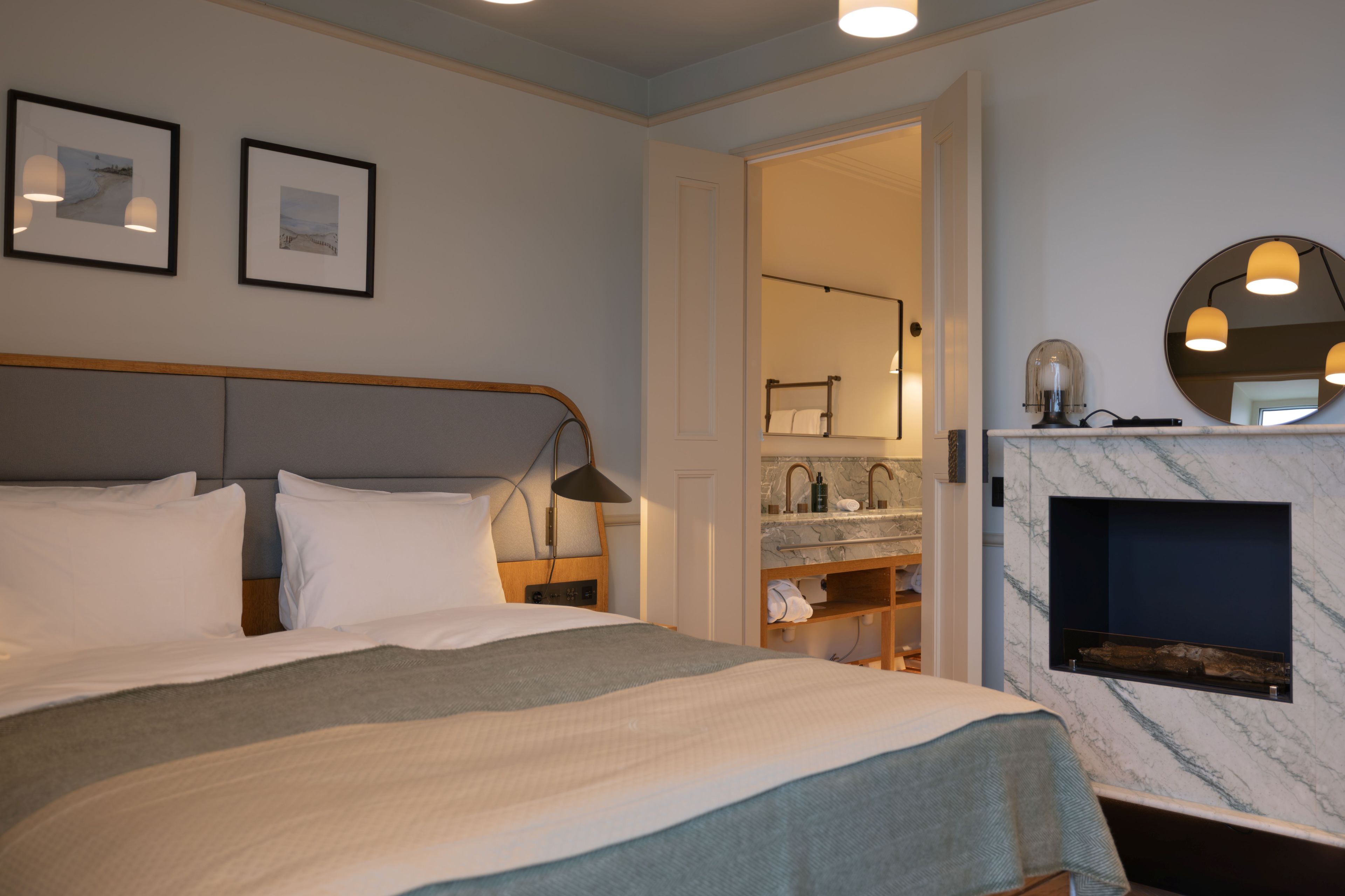 Una habitación de hotel con cama, baño con lavamanos de mármol y chimenea.