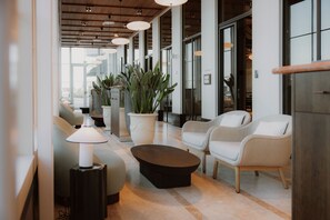 Een moderne lobby met zitplaatsen, plantenpotten en een salontafel.