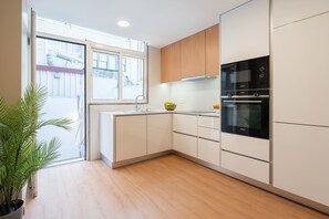 Eine moderne Küche mit weißen Schränken, einem eingebauten Backofen und einem Fenster mit Außenblick.