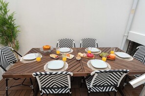 Ein Holzespeisetisch ist gedeckt mit Tellern, Gläsern und Speisen, umgeben von schwarzen und weißen Stühlen mit Muster.