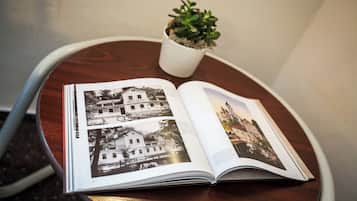 Un livre ouvert, contenant des photographies en noir et blanc de bâtiments, est posé sur une table ronde en bois.