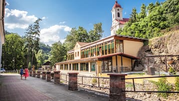 A building with a tower, a covered walkway, and a rocky hillside.