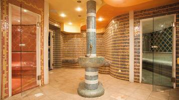 A spa area with mosaic walls, a central column, and a glass-enclosed shower.