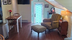 Een ruime woonkamer met een houten plafond, een eettafel met stoelen, een bank en een vloerkleed met dessin.
