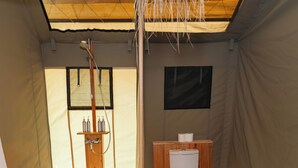 Una carpa con una cama de madera, un inodoro y una zona de ducha.
