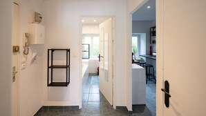 A hallway leading to a bathroom with a toilet, sink, and shower. There is a door on the right leading to a kitchen area with a counter and stools. - Apartment "L'Atelier - Near Train Station" with Wi-Fi (Mulhouse)
