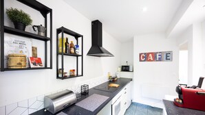 A modern kitchen with black countertops, a stainless steel toaster, a black range hood, and a 'CAFE' sign on the wall. - Apartment "L'Atelier - Near Train Station" with Wi-Fi (Mulhouse)