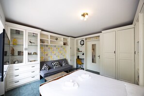 Un dormitorio con cama, sofá, armario y aparador con puertas de vidrio.