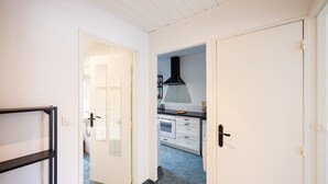 A hallway leading to a kitchen with white cabinets, a black range hood, and a tiled floor. - Apartment "L'Atelier - Near Train Station" with Wi-Fi (Mulhouse)