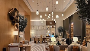 A modern hotel lobby with a checkered floor, multiple seating areas, and a central dining space.