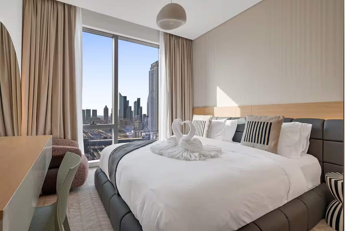 A hotel room with a large bed, a desk, and a view of a cityscape.