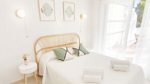 Et soveværelse med seng, puder, et natbord og vægmonteret belysning.