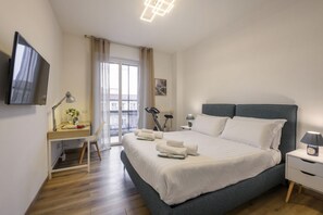 A bedroom with a bed, bedside tables, a desk with a lamp, a chair, and a TV mounted on the wall. - Modica, 16 - Apartment near Iulm (Milan)