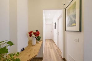 Ein Flur mit einer hölzernen Bank, einer Blumenvase und einem gerahmten Bild an der Wand.