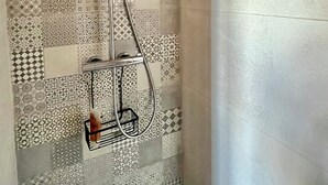 A shower with a patterned wall, a handheld showerhead, and a metal rack. - REFLETS DE L'YONNE, independent bed and breakfast on the banks of the Yonne in Sens (Sens)