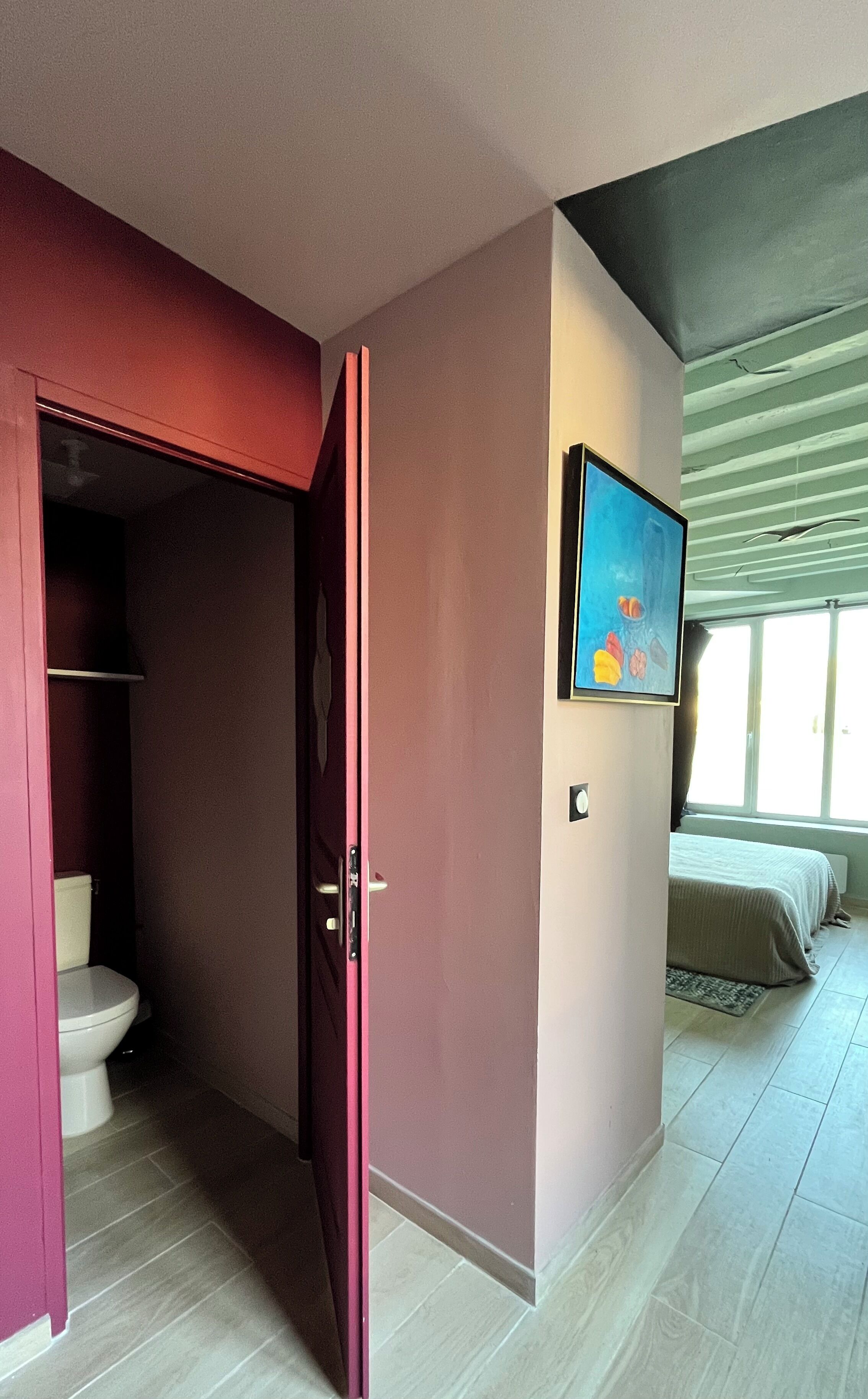 Une chambre avec un lit, un tableau et une salle de bain équipée de toilettes et d’une douche.
