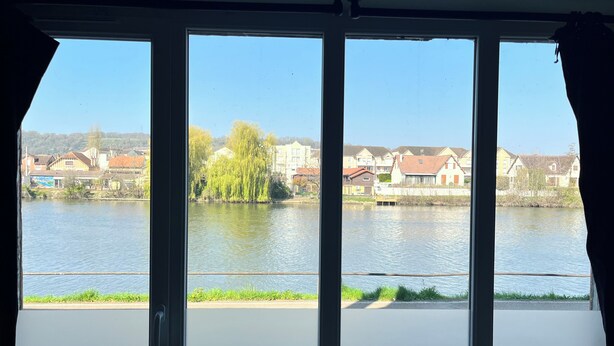 A view through a window with a river, houses, and trees. - REFLETS DE L'YONNE, independent bed and breakfast on the banks of the Yonne in Sens (Sens)