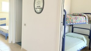 A room with a bunk bed, a door leading to another room, and a wall plaque. - SE182 - Senigallia, three-room apartment facing the sea with balcony and parking space (Senigallia)