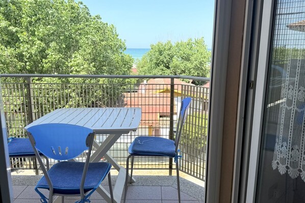 Un balcon avec une table et des chaises, une vue sur la mer et une clôture.