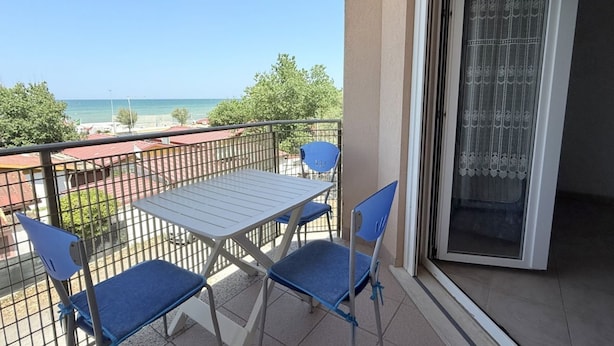 A balcony with a table and chairs, a view of the sea, and a door with a patterned curtain. - SE182 - Senigallia, three-room apartment facing the sea with balcony and parking space (Senigallia)