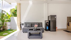 A modern living room with a grey sofa, a coffee table, and a black refrigerator. - Widhiana Villa Ubud (Ubud)