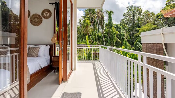 A balcony with a bed, white railing, and lush greenery in the background. - Widhiana Villa Ubud (Ubud)